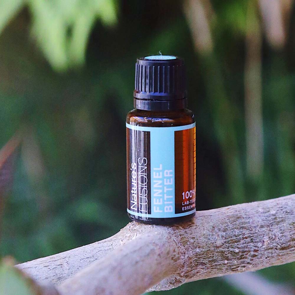 fennel essential oil bottle balanced on tree branch