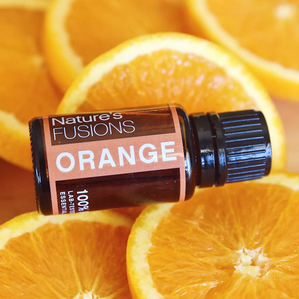 orange essential oil bottle resting on orange slices
