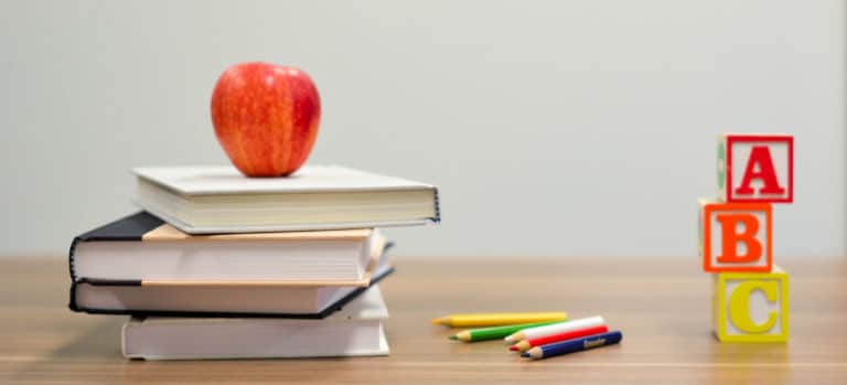 desk with books, an apple, colored pencils, and blocks