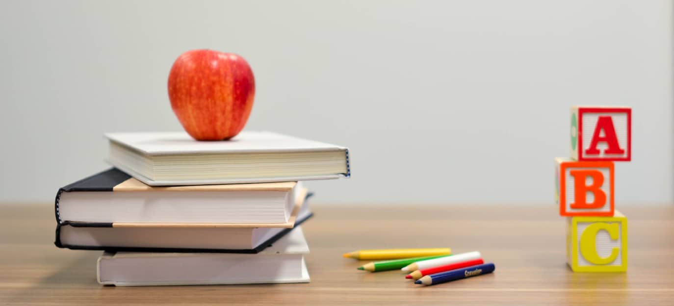 desk with books, an apple, colored pencils, and blocks