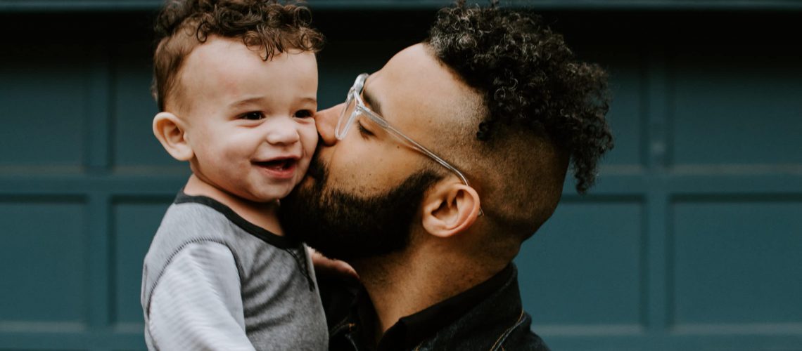 father kissing toddler