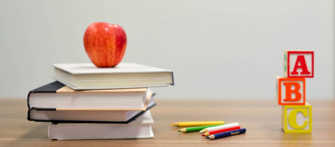 desk with books, an apple, colored pencils, and blocks